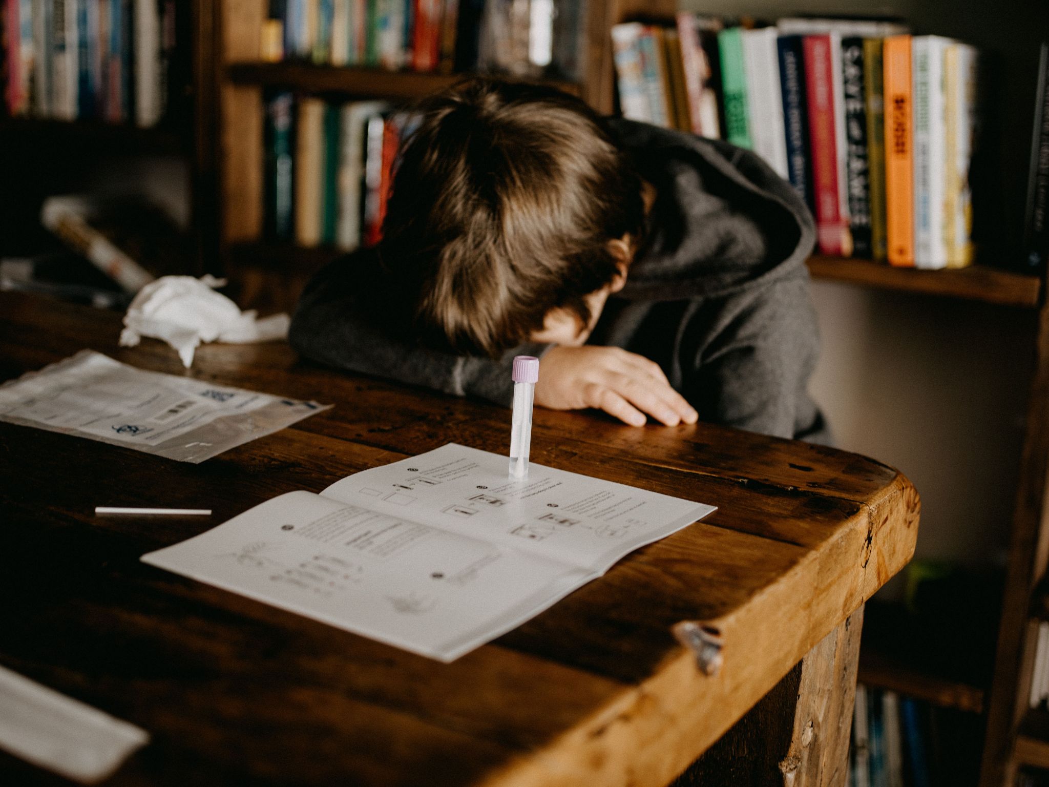 Photo, boy with his head on the table in front of a Covid-19 test